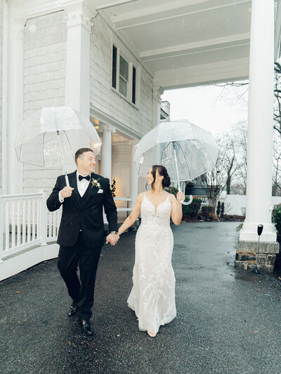 Couple walking and holding umbrellas taken by film and digital wedding photographer