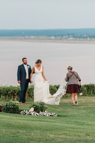 behind the scenes of wedding photographer helping bride with train