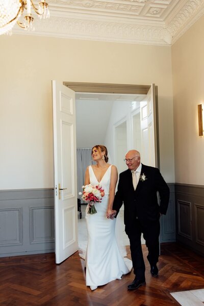 Bruid wandelt binnen met vader op bruiloft door trouwfotograaf Linda Photography
