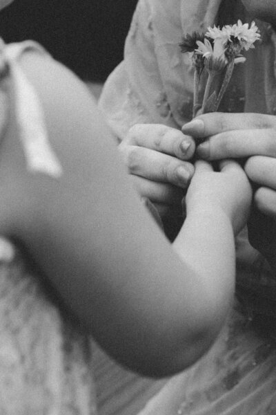 Close-up of little girl handing mom garden flowers, captured in a family session
