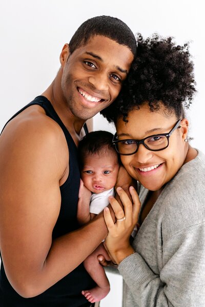 Gorgeous African American couple smiling at the camera with their newborn baby during photos in pensacola fl