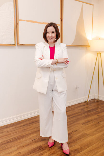 Woman posing for photo wearing pink shirt and white blazer