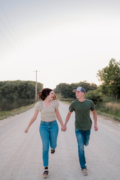 Man and woman smile at each other while holding hands and walking toward the camera.