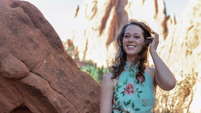 Rivka Rothstein, voice artist, smiles and stands in front of red rock
