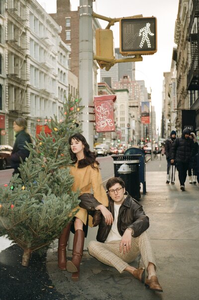 couple sitting on the street with a christmas tree