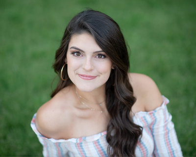 High school senior girl smiles for photo in off the shoulder blouse