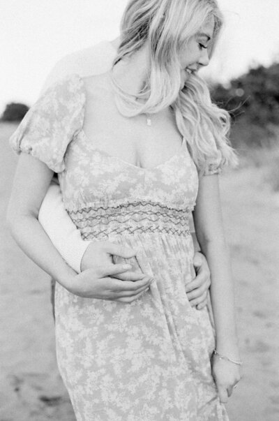 A black and white close up of a woman wearing a puffed sleeve dress at her maternity session in Seattle.