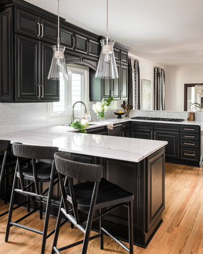 Contemporary kitchen in Lake Norman, NC, with black cabinetry, marble countertops, and stylish lighting.