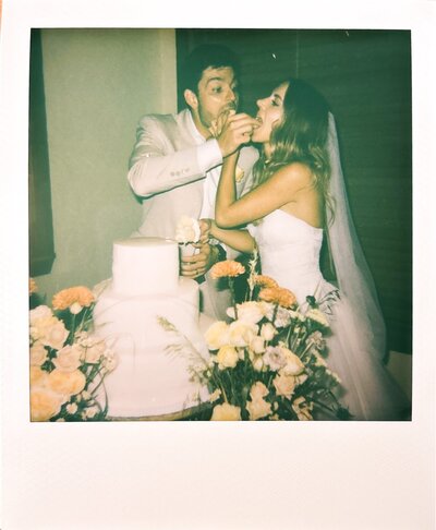 A Polaroid of the bride and groom feeding each other their wedding cake.