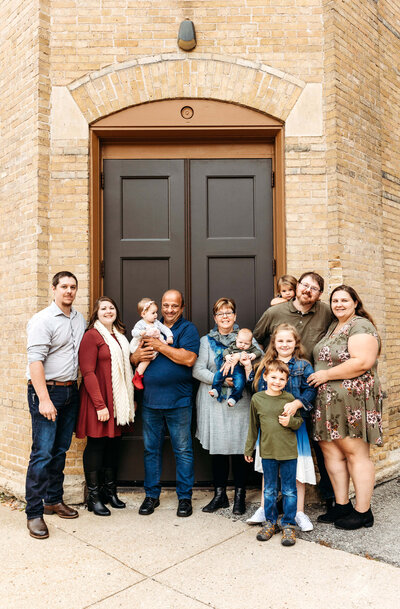 Large extended family standing in front of a large door together in downtown Oshkosh.