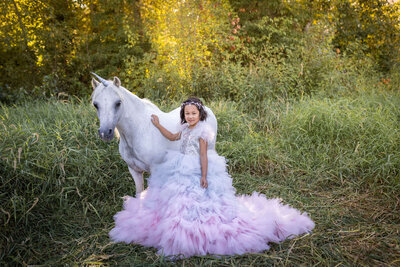 Girl in giant puffy dress touching unicorn