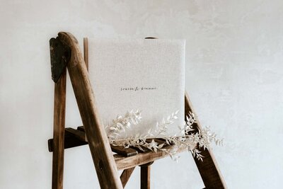 Leinengebundenes Hochzeitsalbum auf einer Leiter erstellt von Hochzeitsfotograf Sarah Thelen