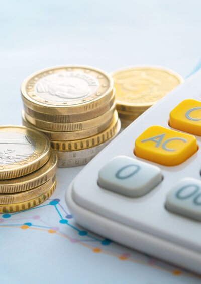 Image of a calculation and stacks of coins deplicting how bookkeeping can save money