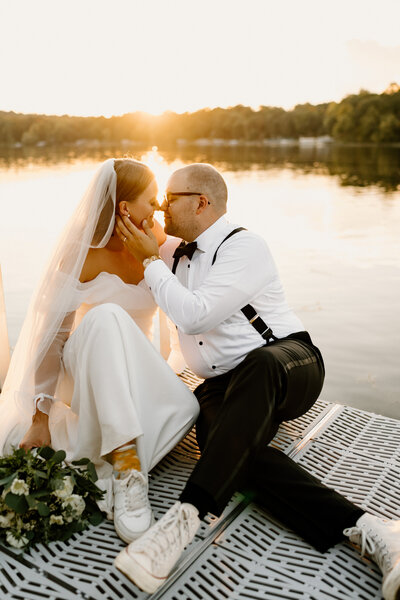 newlyweds sit and kiss on dock