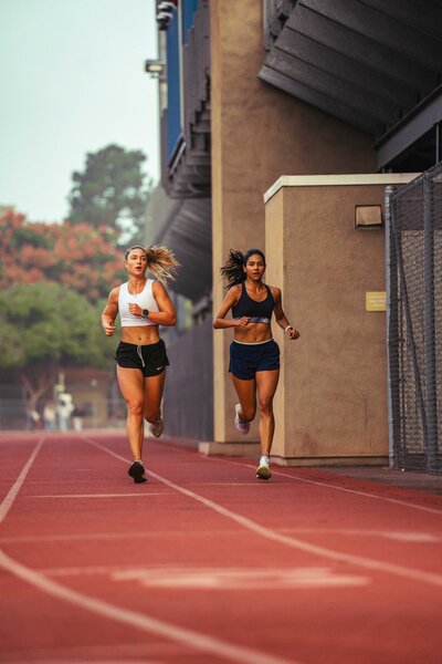 Two females running side by side on a track