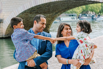 Indian family during a Paris family photoshoot on Île Saint-Louis, smiling and enjoying a quiet moment together in the city center.