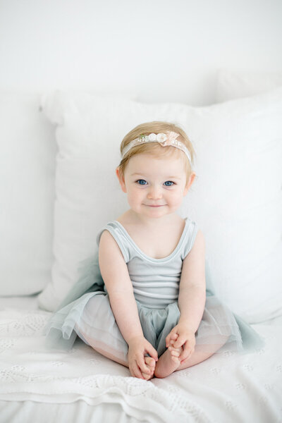 Baby in ruffled romper and crocheted hat sitting in moses basket for photos in a portrait studio in stamford CT