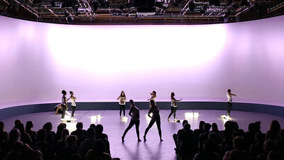 Several dancers on a stage in front of an audience performing modern dances