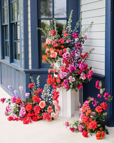 Bold pink, coral, and purple floral installations styled in front of a storefront, reflecting Bloom Bar’s signature Austin window dresser and retail design aesthetic.