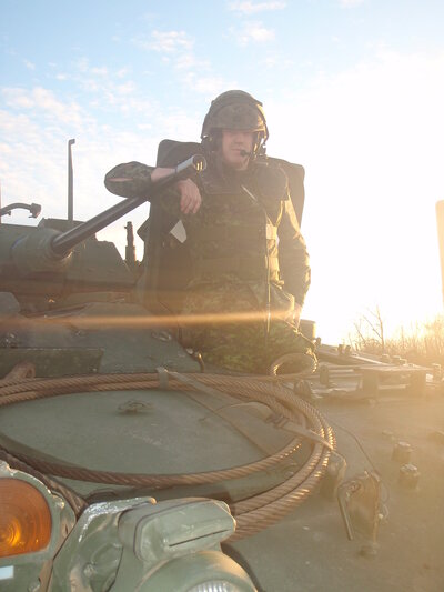 Alexander Cave on infantry tour positioned on an armored vehicle, highlighting tactical coordination