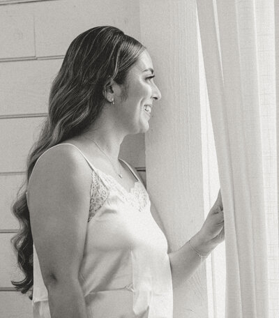 Bride looking out window while getting ready