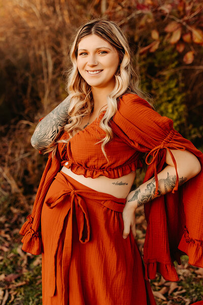 Portrait of Destiny Roth, Cleveland TX boudoir and lifestyle photographer, wearing a rust dress outdoors