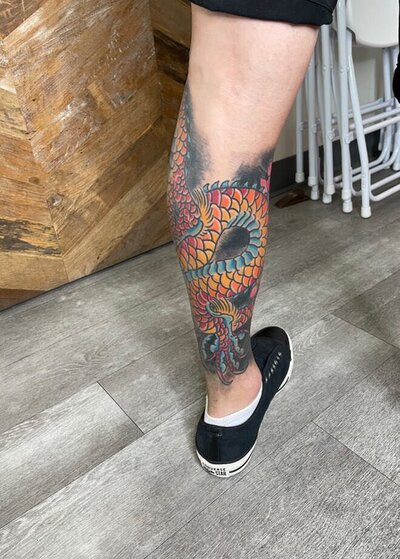 Tattoo of multicolored snake on calf