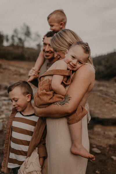 A family of five holding each other at sunset. 