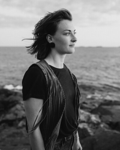 Nainen seisoo rantakalliolla ja katsoo kaukaisuuteen Suomenlinnassa Helsingissä