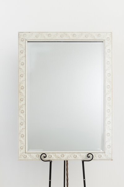 White beaded frame mirror on black easel stand