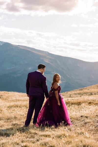 Bride and groom walk along mountainside during elopement day sunset.