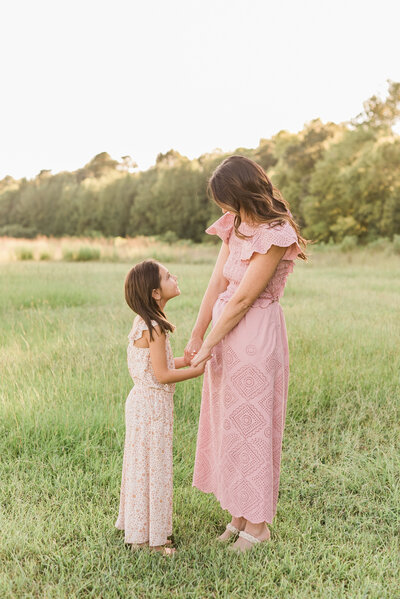 Mom and daughter hold hands in a field during their Wake Forest family photography session. Photographed by Family Photography Raleigh A.J. Dunlap Photography.