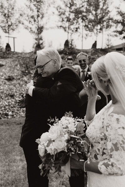 Emotional moment between bride and family, as she wipes a tear from her face.