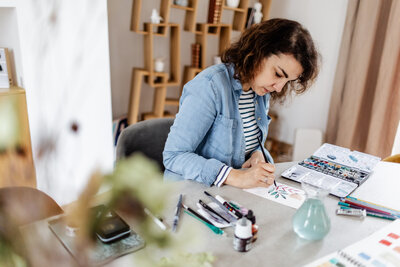 A watercolor artist painting in her studio.
