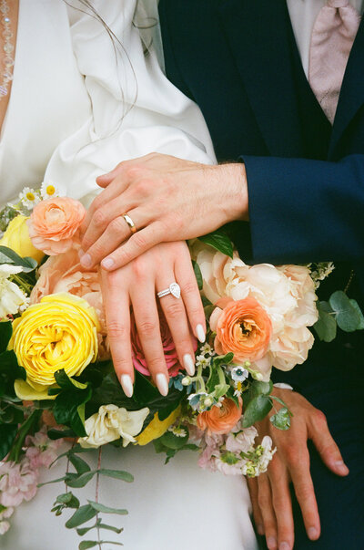close up on the groom and bride's hands with the bouquet and wedding rings
