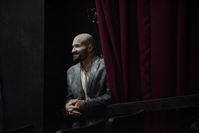 A person smiling from behind a curtain