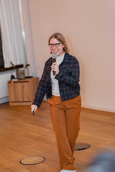Stephanie holds a microphone and slide clicker while presenting.