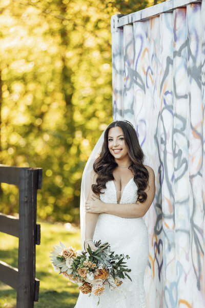 The Hamilton Manor | Bride posing with flowers by fence during summer wedding photo | Hamilton Township, New Jersey