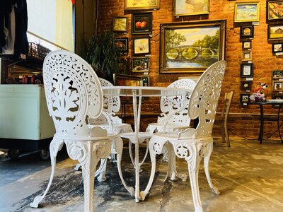 Bakery Scene inside Bebop's Bakery with white antique table and chairs and art paintings on the wall.