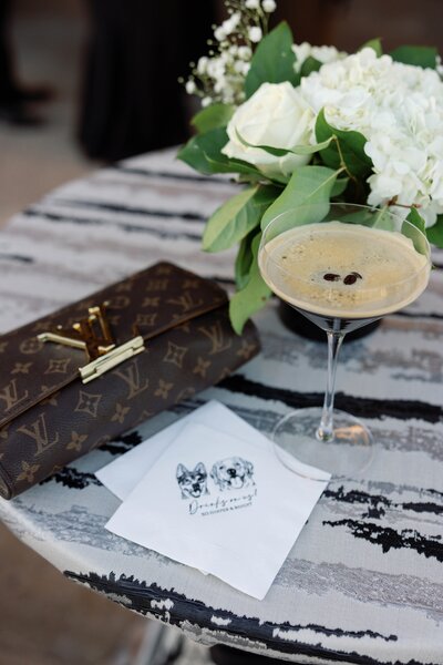 espresso martini and designer clutch styled on cocktail table with custom bar napkins