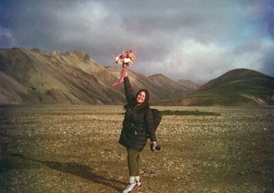 Mariah holding her camera in one hand and a bouquet of flowers in the other