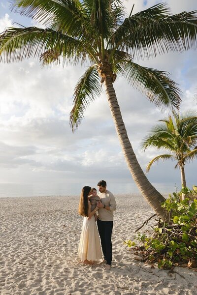 family standing under palm tree, taken by family photographer naples