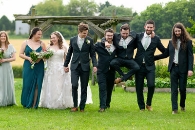 A groomsmen being silly during group shots at a wedding in St.jacbos, Ontario.