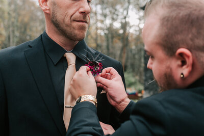 groomsman pinning boutonniere at outdoor wedding in Boston
