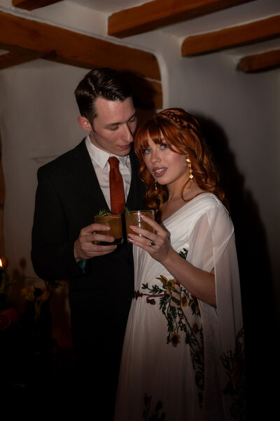 Couple toasting drinks during their intimate indoor elopement in Utah, captured by Lamblight Photography