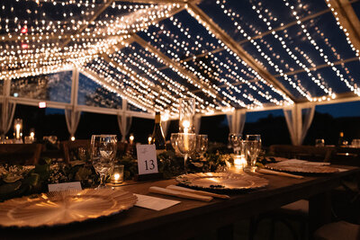 A documentary-style photo featuring ambient light, natural editing, and cozy romantic string lights under an outdoor tent.
