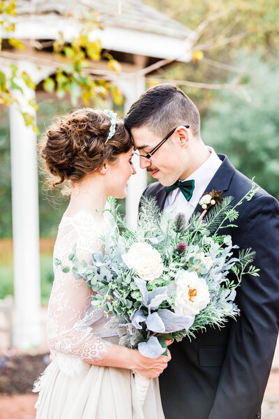 Bride and Groom touching foreheads together with beautiful bouquet