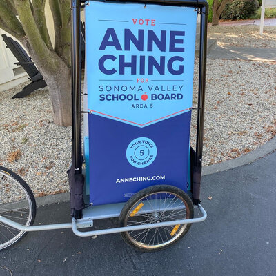 Sign on wheels advertising Anne Ching for School Board