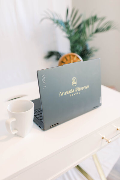 Laptop sitting on desk with Amanda Therese Travel logo