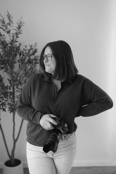 A person looking off to the side and holding a camera with one hand 